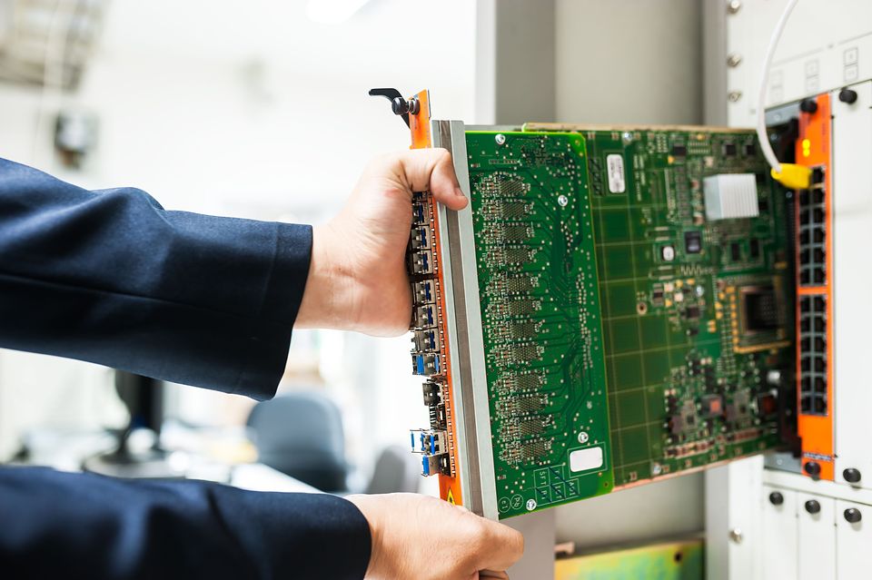 A technician sliding a network card into a server rack.