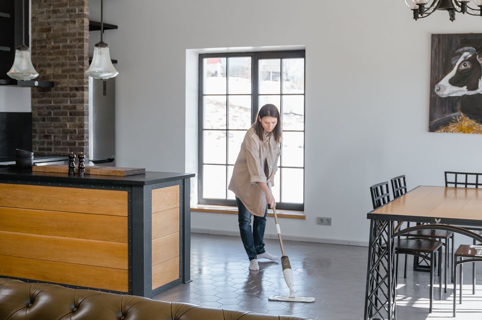 A cleaner mopping the floor of a large, bright room.