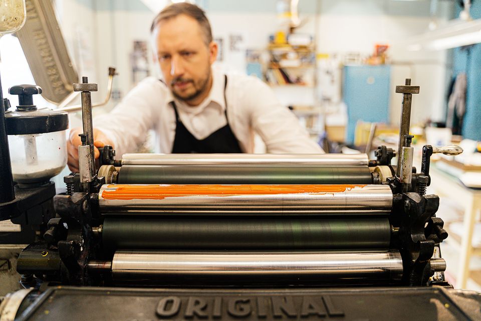 A printer working at a printing press in a print shop.
